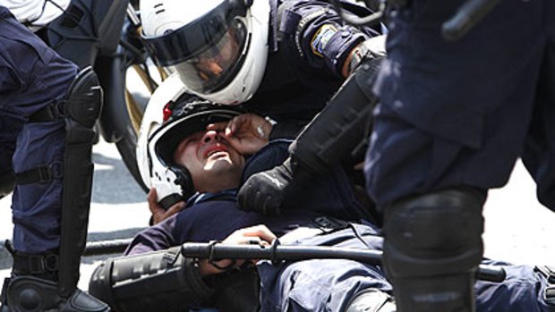 An injured policeman lies on the ground during a rally in Athens.