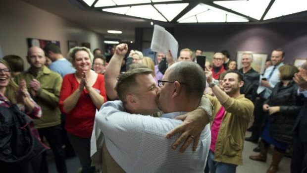 Chris Serrano, left, and Clifton Webb kiss after being married, as people wait in line to get licenses outside of the marriage division of the Salt Lake County Clerk's Office in Salt Lake City.