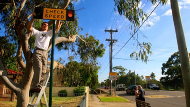 "It's not just for the safety of the kids, it's also for fairness on drivers''...Peter Olsen installs a sign near Cartwright Public school.