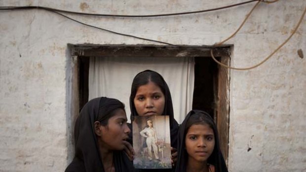 Family pleas ... Esha, 12, left, Sidra, 18, and Eshum, 10, the daughters of Pakistani Christian woman Asia Bibi pose with an photo of their mother.