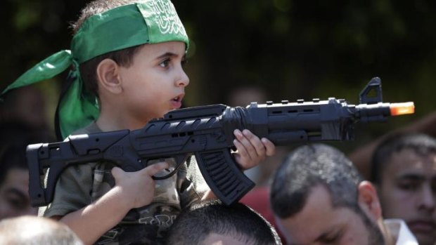 A Palestinian boy holds a toy gun as he participates in the Hamas rally.