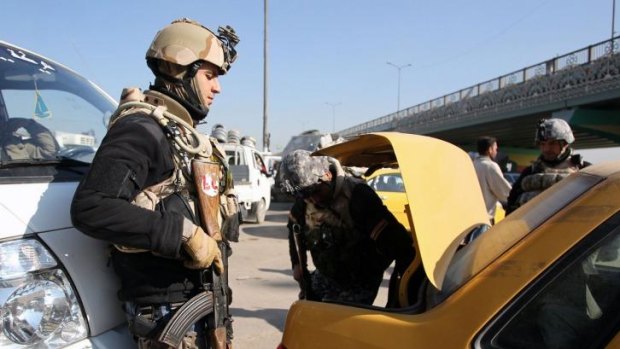 Iraqi security forces search the boot of a car at a checkpoint in Baghdad as Iraq witnessed a series of attacks in and around the capital.