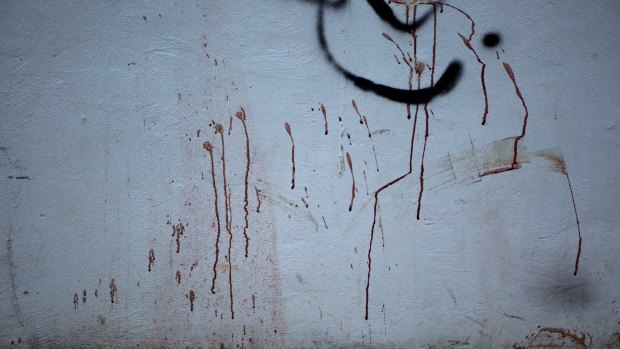 Blood splatters stain a concrete wall and the sand below on a public walkway to the beach next to the club.