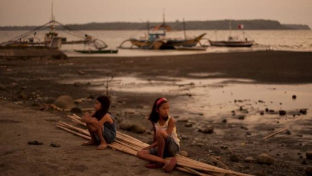 Hard times: Children sit in front of idle fishing boats on the shore of Masinloc, a town in the Philippines that depends on catches from the disputed Scarborough Shoal area.