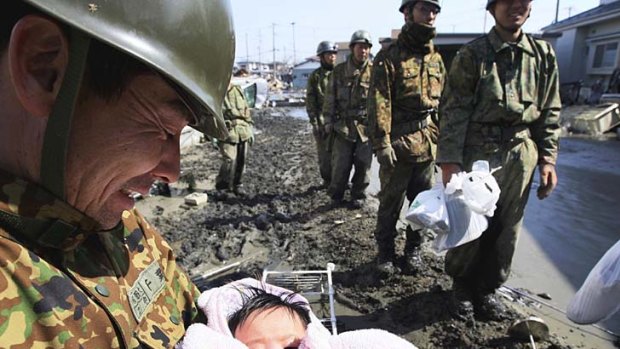 A  Japan Self Defence Force  member takes care of a four-month-old girl he rescued in Ishinomaki, northern Japan.