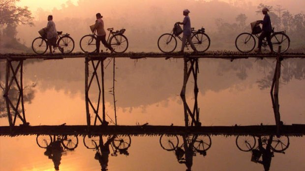 Indonesian villagers push their bicycles across a bamboo bridge as sun rises behind them outside Yogyakarta city in Central Java.