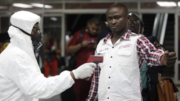 A Nigerian port health official uses a thermometer on a worker at the arrivals hall of Lagos airport.