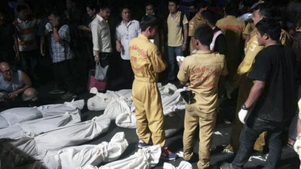 Deadly plunge ... Thai emergency workers and onlookers stand next to bodies of 30 victims of the bus crash, wrapped in white cloths.