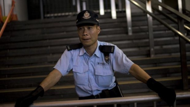 A police officer looks at pro-democracy protesters rallying next to the Hong Kong police headquarters in the Wan Chai area of Hong Kong.