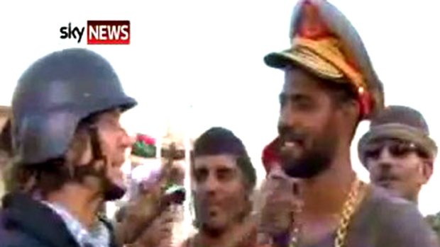 A rebel fighter dons a cap and gold chain reportedly seized from Gaddafi's quarters.