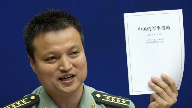 China's Defence Ministry spokesman Yang Yujun holds up China's Military Strategy white paper during a press conference in Beijing on Tuesday.