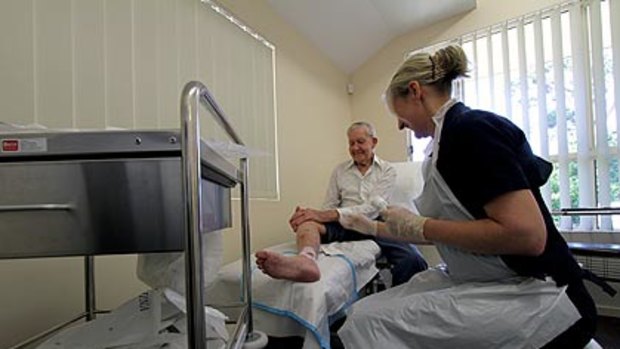 Ken Matches has his leg wounds dressed by registered nurse Sarah Aldridge at the Spiritus Leg Club in Nundah.