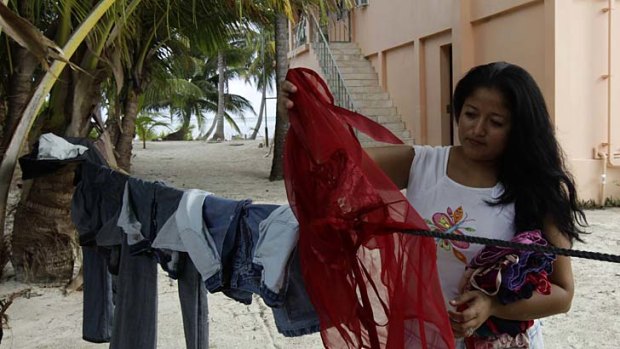 Reyna Galdamez, 24, an employee of dead American businessman Gregory Faull, collects clothes outside of Faull's home in San Pedro.