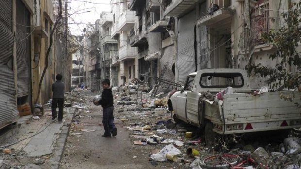 Children play along a street amid damaged buildings in the besieged area of Homs.