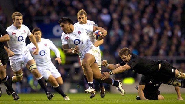 England centre Manu Tuilagi breaks a tackle from All Black flanker Richie McCaw.