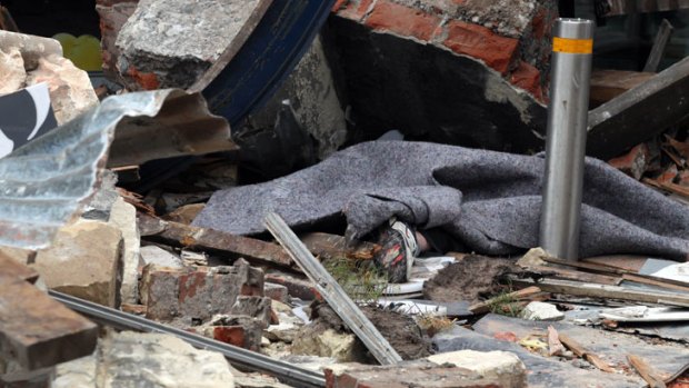 Olivia Cruickshank lies in the rubble of the Christchurch earthquake; her foot sticks out from the blanket rescuers covered her with after taking daughter Abbie to hospital.