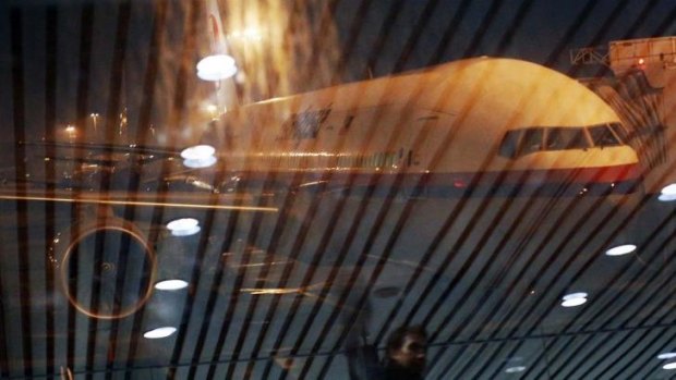 Malaysia Airlines Boeing flight MH318 to Beijing sits on the tarmac as passengers are reflected on the glass at the boarding gate at Kuala Lumpur International Airport.