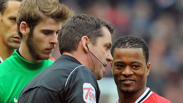 Referee Phil Dowd speaks to Patrice Evra after Liverpool striker Luis Suarez failed to shake hands with Manchester United's captain.