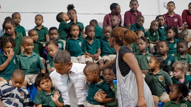 Otherwise engaged ... a boy kisses a girl while Barack Obama visits a school in Florida.