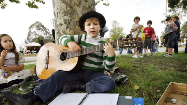 Busker John Bennett, 8, an enthusiastic talent with the ukulele and guitar, works through his song list for an appreciative audience at the Yea festival.