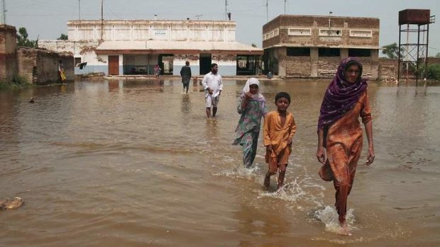 Monsoon rains: A family wades through flood waters in Pakistan.