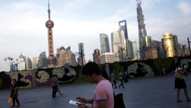 A man checks his iPad in front of the financial district in Shanghai, China.