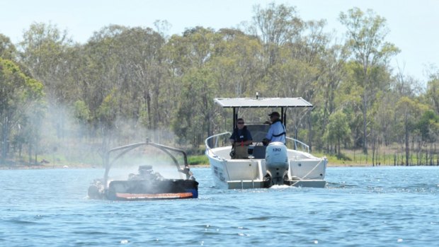 A smouldering boat is towed to the shore at Atkinsons Dam on Wednesday.