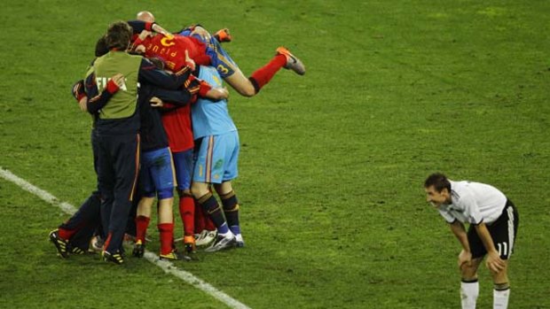 Little chance to shine ... Miroslav Klose looks dejected as Spain's players celebrate reaching the final.