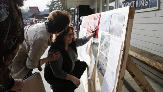 Brenda Neal, right, looks at aerial photos of the landslide for her missing husband's car.