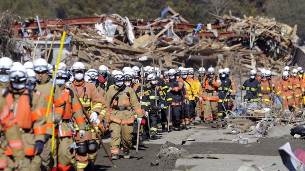 On the move ... firefighters march through Rikuzentakata to search for victims yesterday. A 15-metre wave virtually wiped the town of 23,000 off the map.