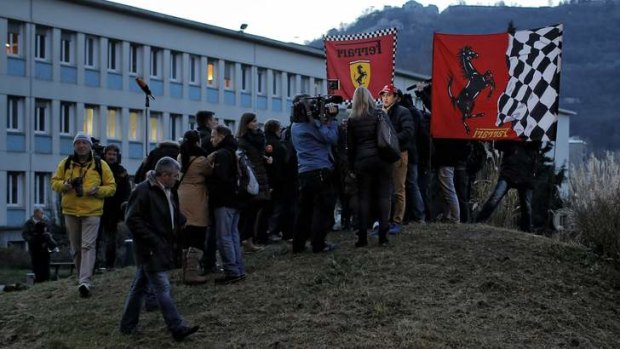 Vigil: Journalists gather around a Ferrari fan outside hospital.
