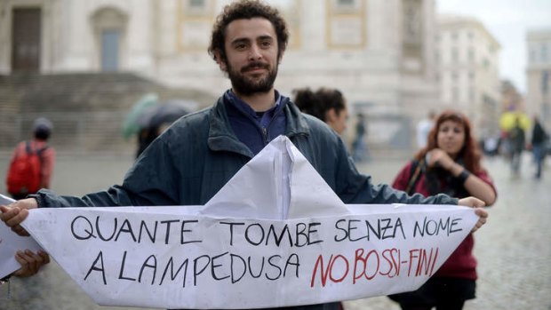 An Italian student holds a paper boat reading "How many tombs without names in Lampedusa, No to Bossi Fini" in reference to the earlier tragedy off Lampedusa island where at least 311 immigrants drowned.