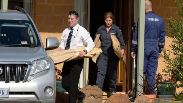 Detectives and forensic officers carrying evidence from the victim's house.