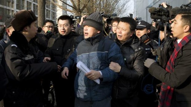 After the verdict: Zhang Qingfang, the lawyer for legal scholar and founder of the New Citizens movement, Xu Zhiyong, is taken away by policemen as he speaks to the media.
