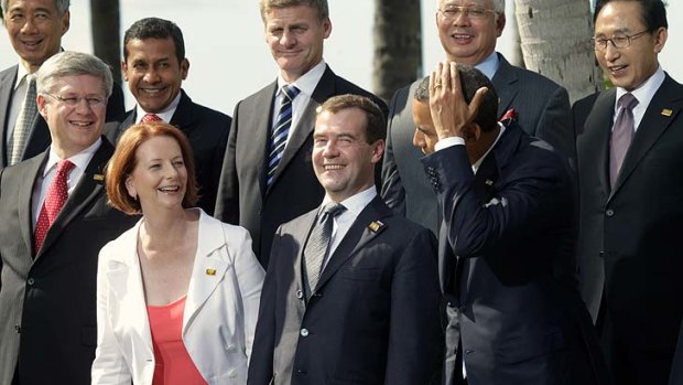 Plenty of smiles but no silly shirts ...  President Barack Obama jokes about grooming his hair with  Julia Gillard during the group photo call at the APEC leaders' meeting in Hawaii yesterday as Russian President Dmitry Medvedev chuckles.