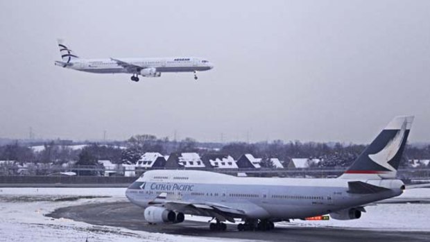 A passenger jet comes in to land as a Cathay Pacific Boeing 747 taxis at Heathrow Airport. Snow and freezing temperatures further delayed flights across northern Europe.