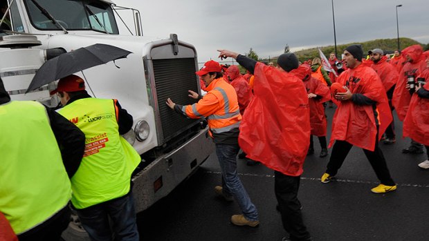 Spiros Cechris jumps in front of a truck as workers block the entrance to Coles' national distribution centre earlier this week.