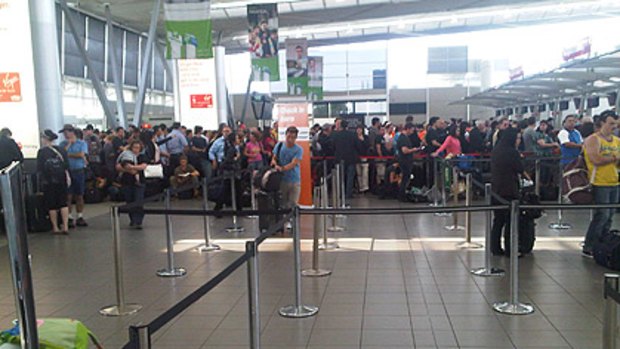 As passengers mass around Virgin Blue's desks at Sydney  Airport, other check-in desks remain empty.