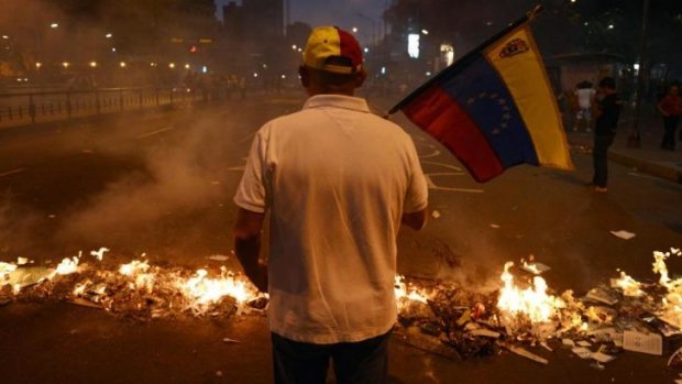 A man holds a Venezuelan flag next to a barricade during an anti-government demonstration in Caracas on February 21.