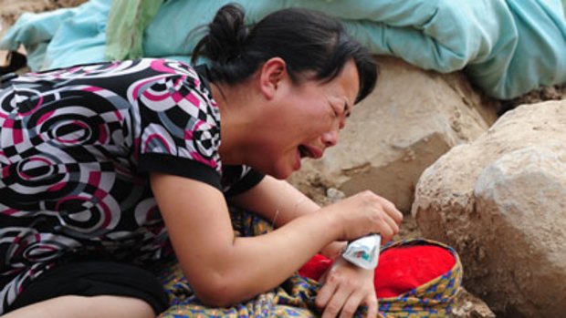 A woman cries over the dead body of her child.