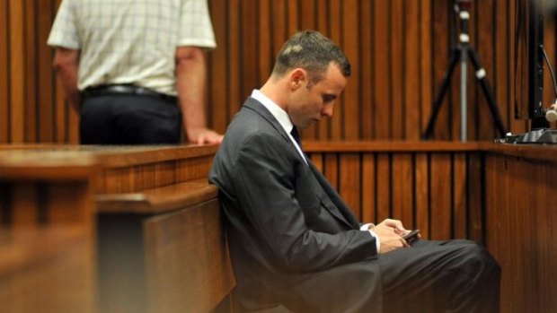 Staying connected ... South African Paralympic athlete Oscar Pistorius texts on his mobile phone as he sits in the dock during his ongoing murder trial.