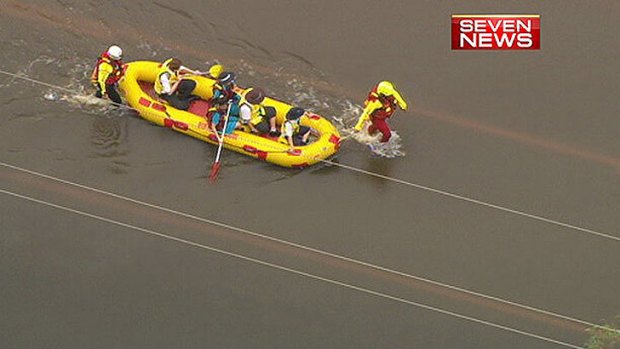 Rescuers take students to school at Acacia Ridge after their bus was stranded on a flooded road.