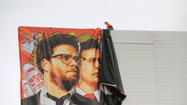Workers remove a poster for The Interview from a billboard in Hollywood, California, a day after Sony announced was cancelling the movie's Christmas release.
