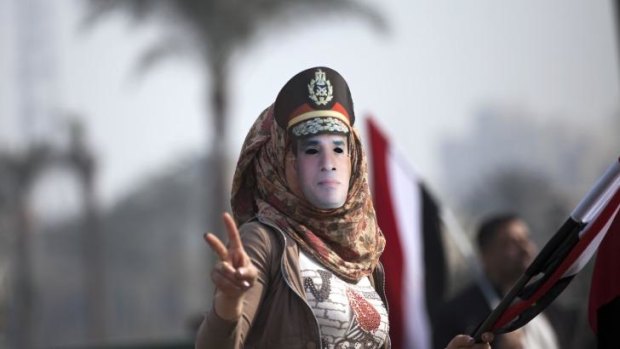 A woman wears a mask depicting Field Marshal Abdel-Fattah Al-Sisi.