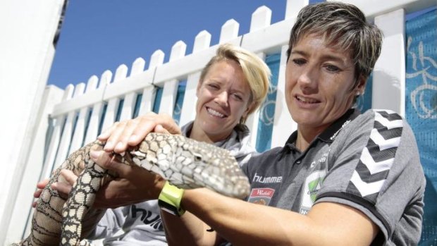Canberra United player Lori Lindsey and coach Elisabeth Migchelsen get to know Cheeky the perentie at the Reptiles Inc display at Floriade.