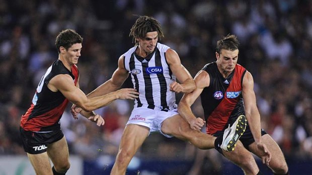 Foot loose: Essendon's Ben Howlett (left) and Jobe Watson (right) do their best to spoil Collingwood star Scott Pendlebury last night.