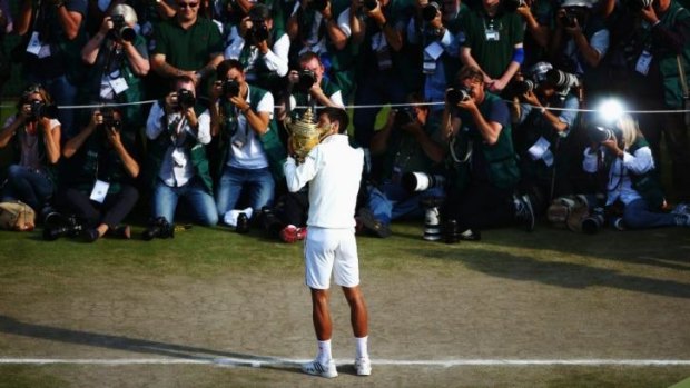 Novak Djokovic shows off the Wimbledon trophy after beating Roger Federer in five sets.