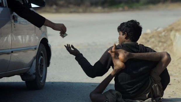 Crippled by polio ... A Pakistani beggar who has been affected by polio receives money from a commuter on a street in Islamabad.