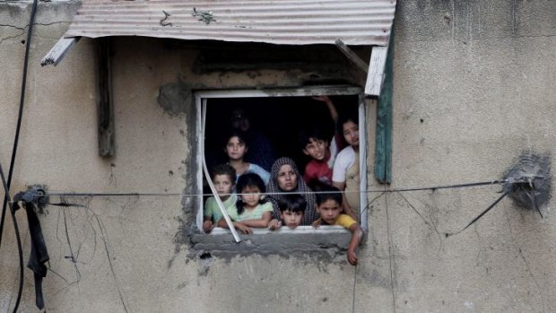 A Palestinian family watches as rescuers search in the rubble of homes destroyed by an Israeli missile strike, in Gaza City.