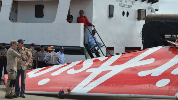 Foreign investigators examine the tail of the AirAsia flight QZ8501 in Kumai on Monday after debris from the crash was retrieved from the Java sea.